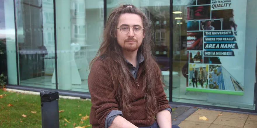 Man sitting outside Leeds Trinity University.