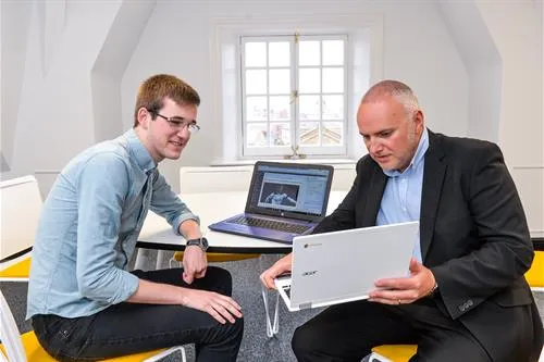 Two men looking at a laptop in an office.
