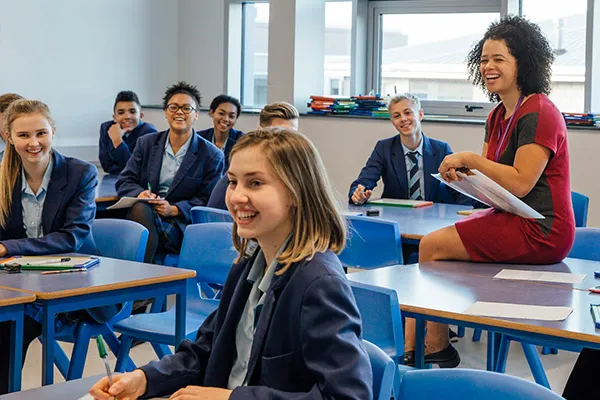 A teacher sitting with her students in a classroom.