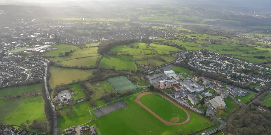 Aerial image of green spaces, buildings, sports field.