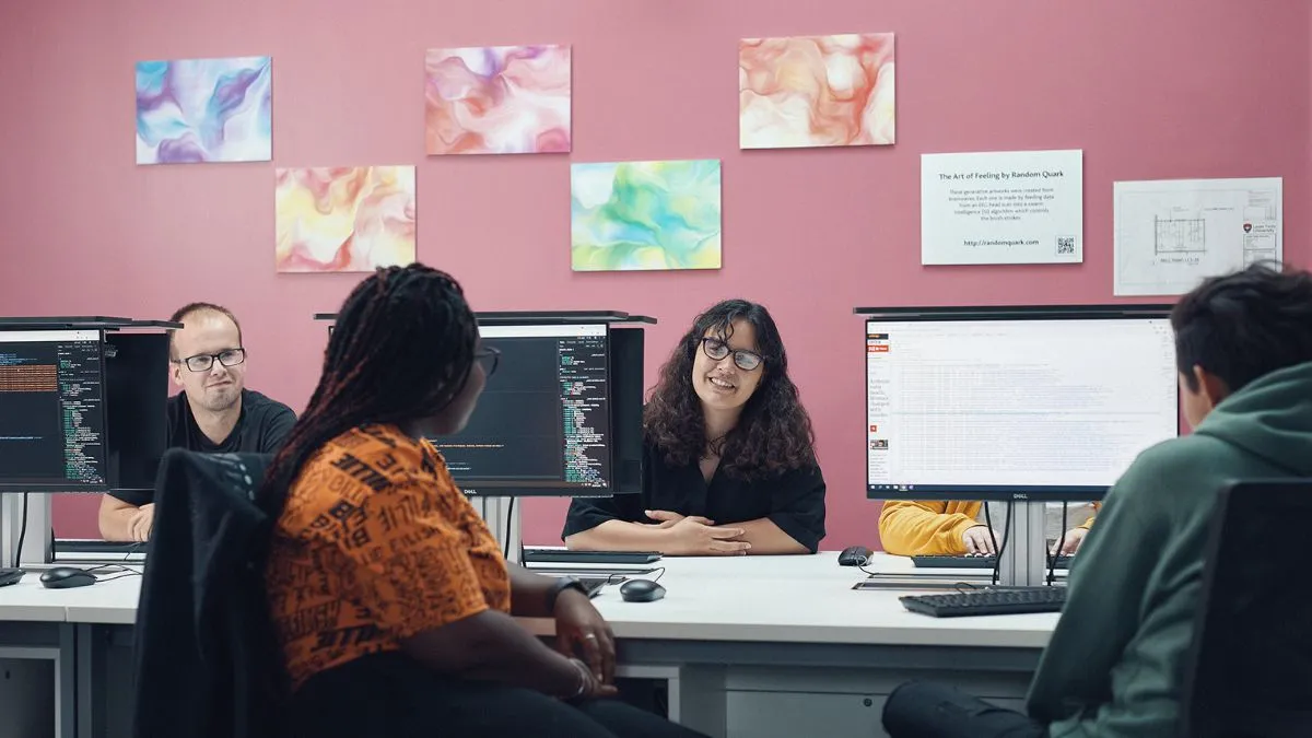 Four students sit in front of computers..