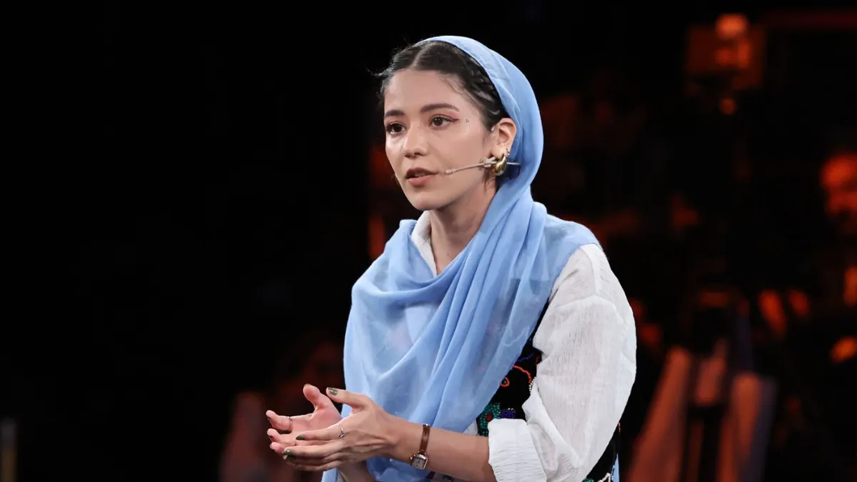 Young woman wearing a blue scarf giving a talk.