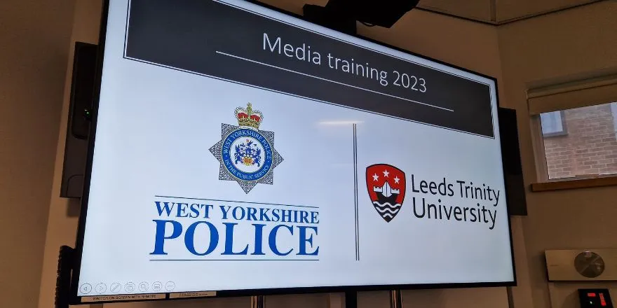 A board displays the logos of the West Yorkshire Police and Leeds Trinity University.