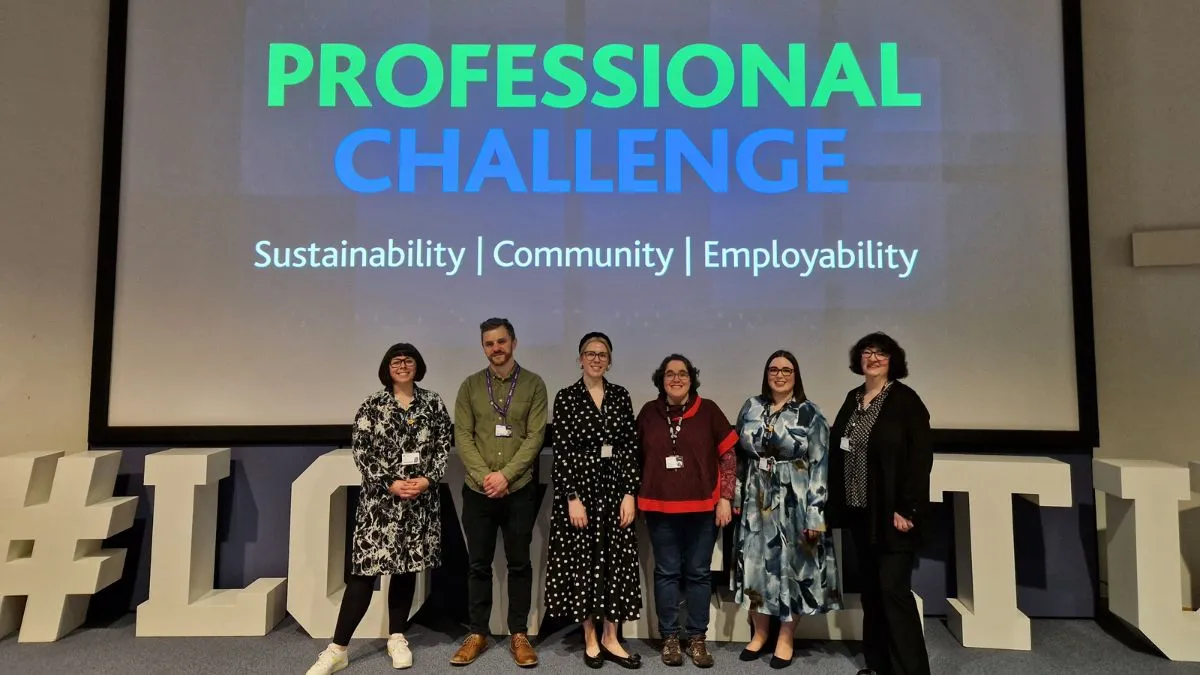 Six members of staff stand in front of a screen displaying the words Professional Challenge.
