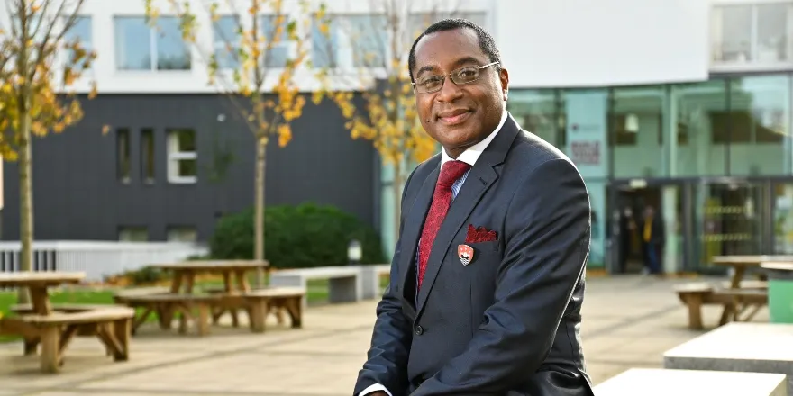 Charles Egbu sitting outside with trees and benches.
