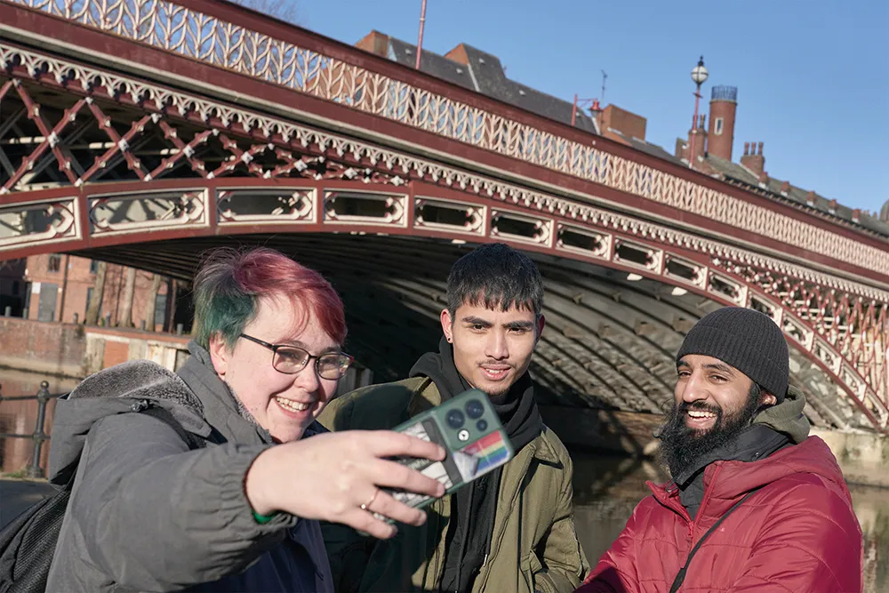 Three student pose for a selfie near Leeds bridge.