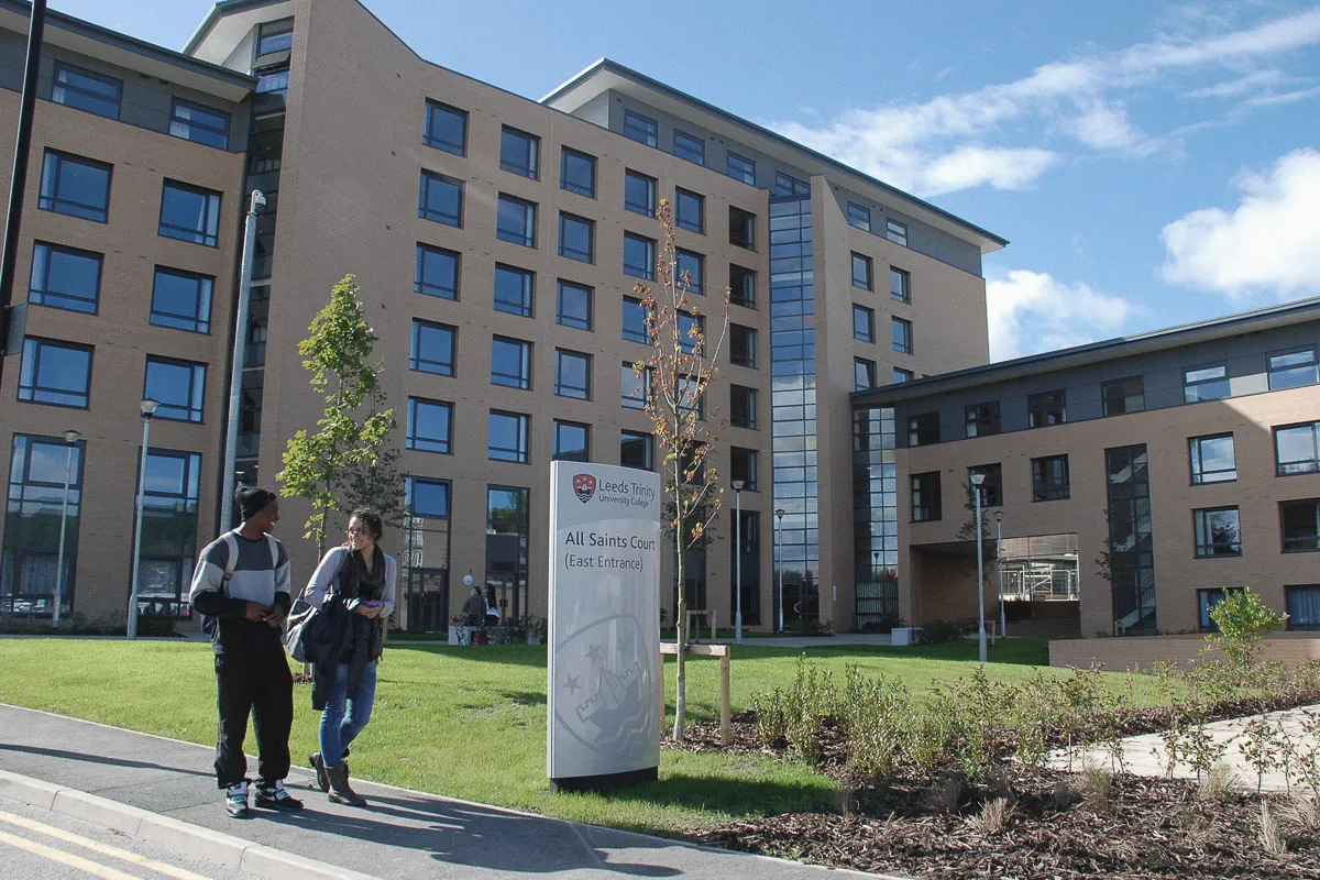 Exterior photograph of All Saints Court with two students walking in front of the building.