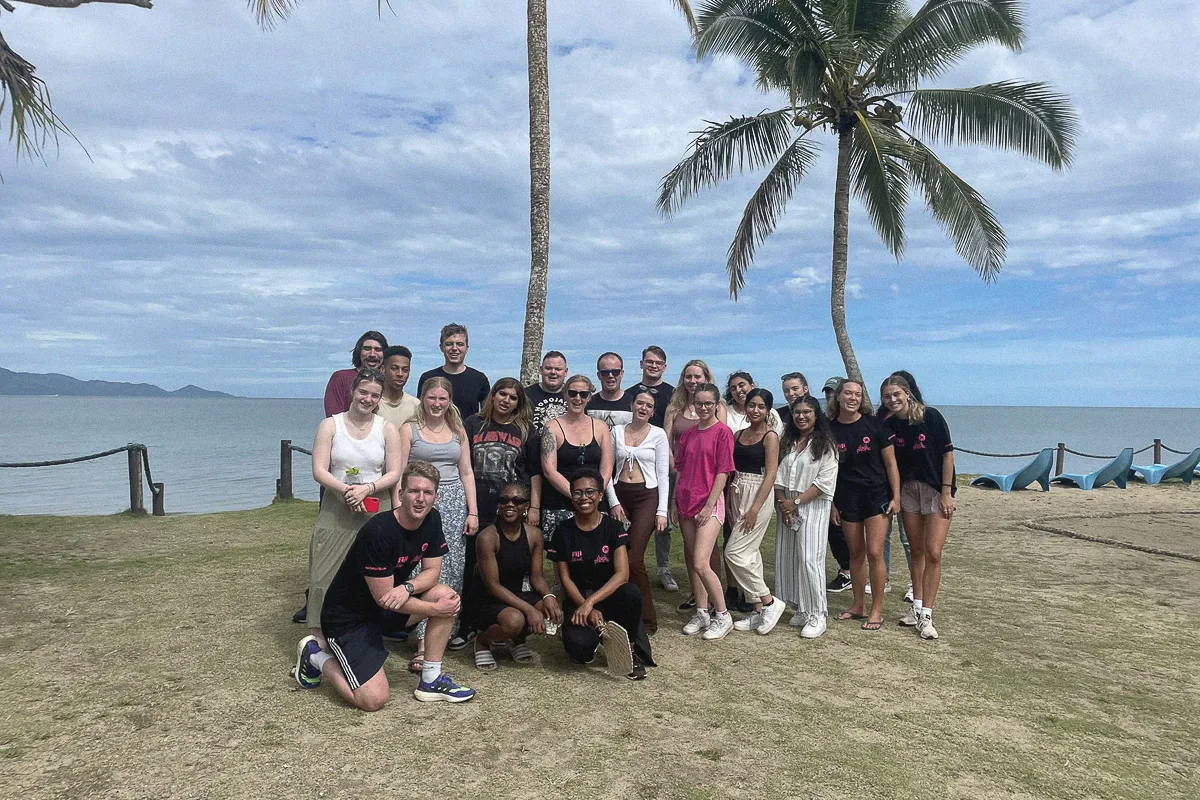 Group photograph of students on a study abroad trip with sea and trees in the background..