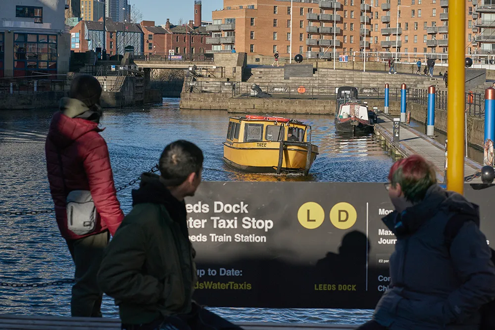 Three students waiting for the water taxi at Leeds Dock.