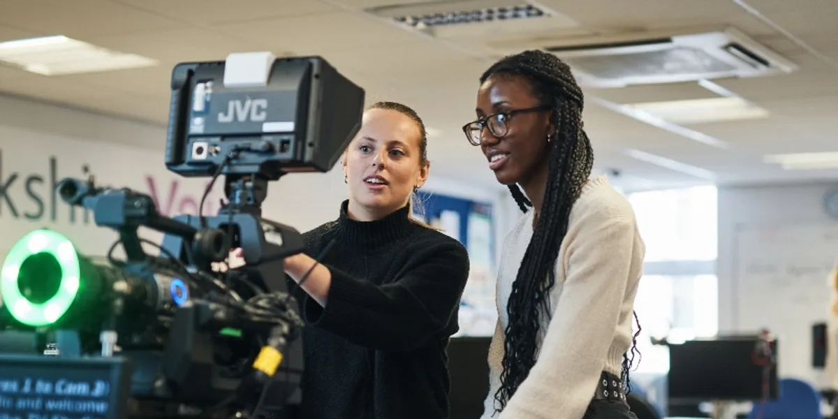 Two female journalism students setting up a camera and autocue.